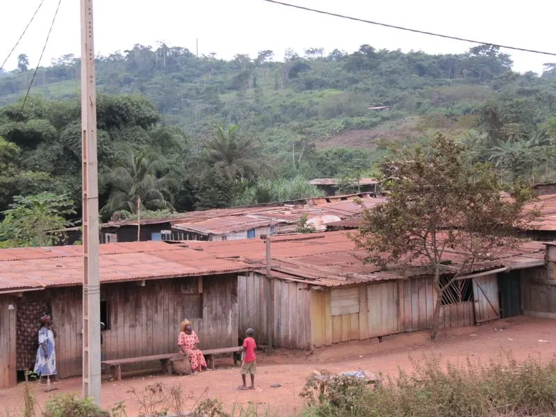 Wooden houses with rusty metal roofs below wooded hills in Lastoursville