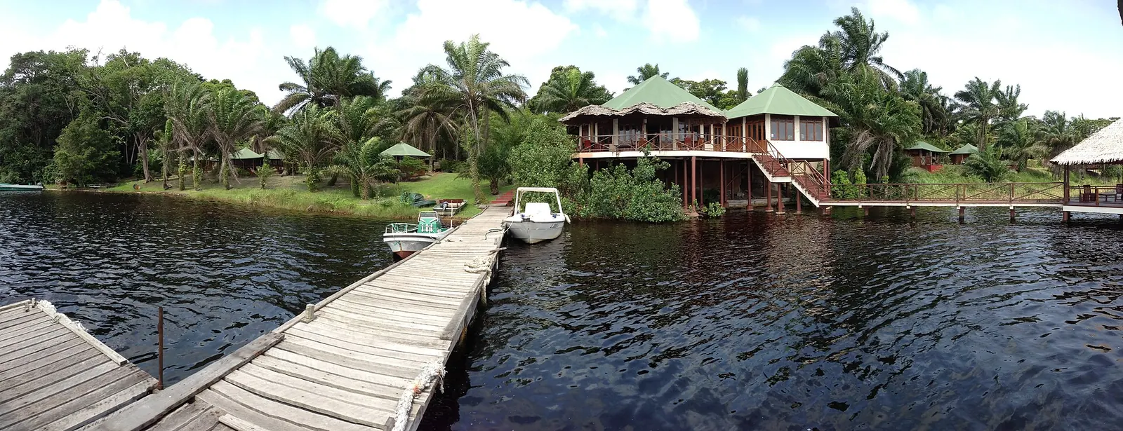 Wooden jetty and lodge buildings on a palm fringed lagoon