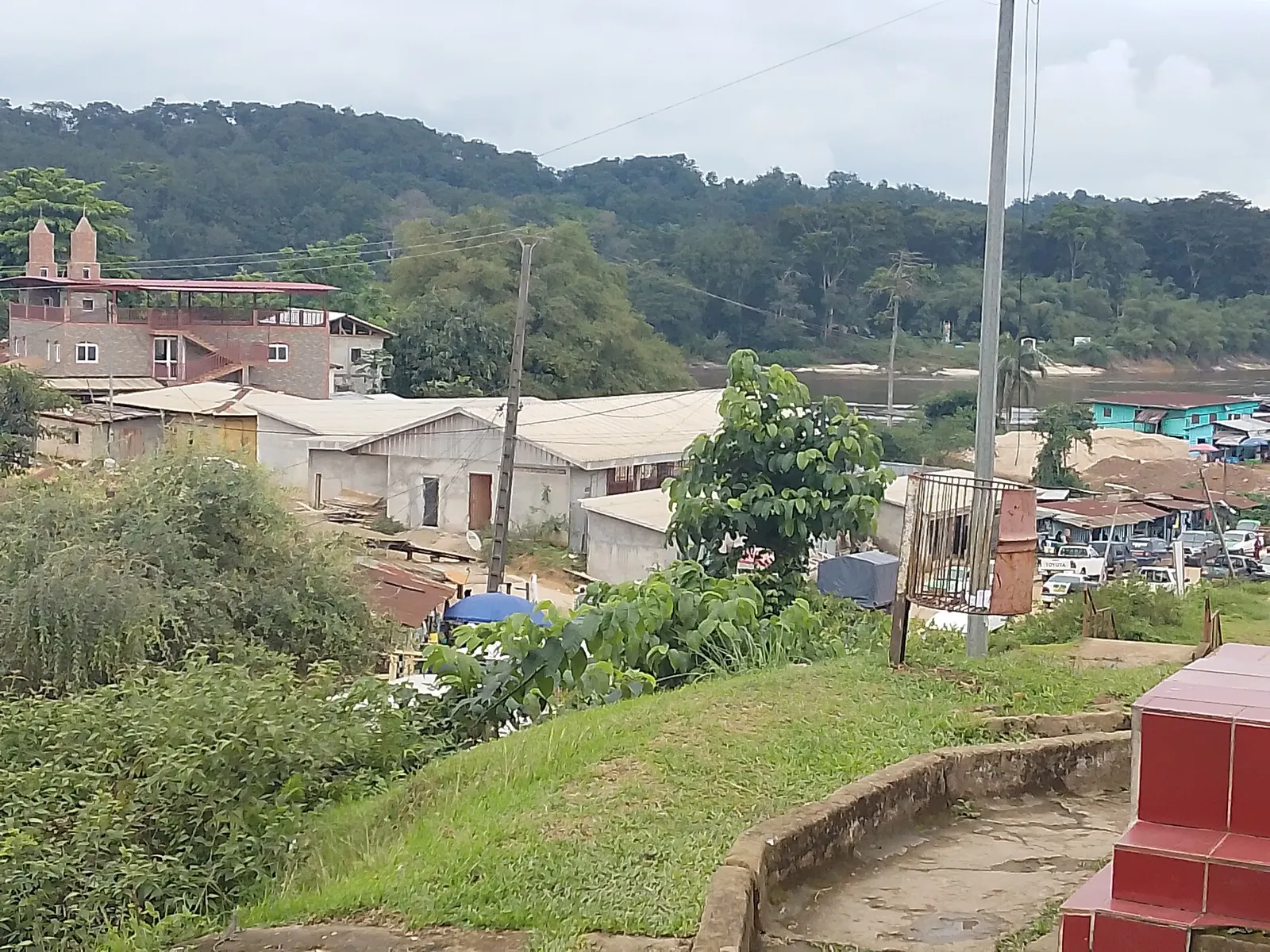 Maisons et bâtiments de Ndjolé sur une colline entourée de forêt