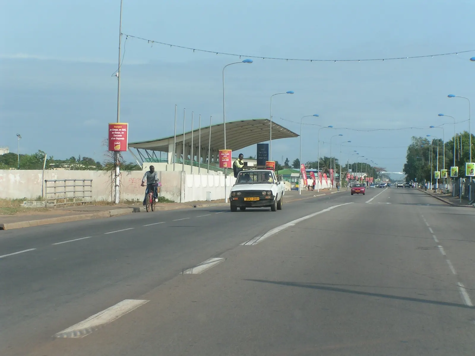 Wide paved avenue in Port-Gentil with a few cars and street lamps