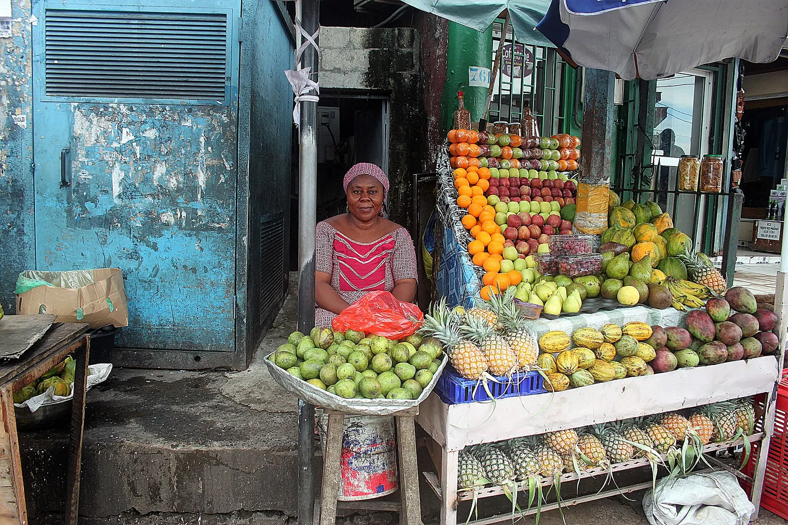 Une commerçante derrière son étal d'ananas, d'oranges et de papayes dans une rue de Libreville